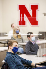 Students separated by plexiglass listen in a classroom as Roberto Stein teaches FINA 475 - Strategic