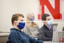 Students separated by plexiglass listen in a classroom as Roberto Stein teaches FINA 475 - Strategic