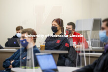 Students separated by plexiglass listen in a classroom as Roberto Stein teaches FINA 475 - Strategic