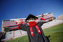 A masked Herbie Husker holding a diploma, poses in regalia to announce spring commencement will be i
