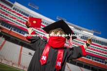 A masked Herbie Husker holding a diploma, poses in regalia to announce spring commencement will be i