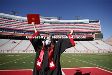 Macy Behrens, senior in advertising and public relations and also graphic design, poses in regalia t