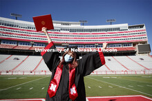 Macy Behrens, senior in advertising and public relations and also graphic design, poses in regalia t