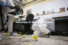 Gracen Korfanty photographs a footprint and Megan Micek dusts for prints as they work the mock crime
