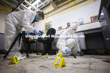Gracen Korfanty photographs a footprint and Megan Micek dusts for prints as they work the mock crime