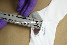 A sock which has a spot which appears to be blood and will be tested is measured as part of collecti