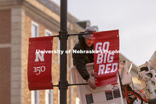 Drew Ehrisman, Construction Supervisor with Landscape Services, slides one of the new banners onto a