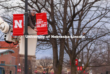 Drew Ehrisman, Construction Supervisor with Landscape Services, slides one of the new banners onto a