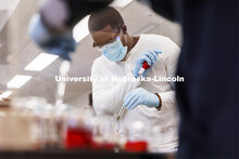 Bill Kabarebe draws up liquid as students perform spectral analysis on colored liquids in the chemis