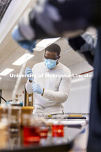 Bill Kabarebe draws up liquid as students perform spectral analysis on colored liquids in the chemis