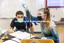 Teagan Gaul adds silica to a burette as Troy Lugn watches. The Chemistry 106 lab experiment will fil