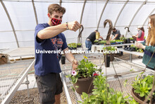 Tom Henry moves a finished hanging basket onto the rack so they can be watered during a club work se
