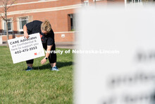 CARE Advocate Melissa Wilkerson places a sign at the Nebraska Union Greenspace. Flags and signs are 