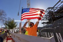 A Hausmann Construction employee unfurls a flag placed on the final steel beam during the topping ou