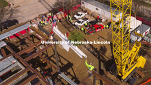 A crane lifts the final beam into the air as Hausmann Construction workers ready to bolt it into pla