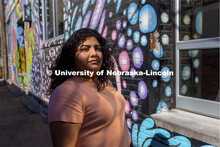 Josselyn Catalan, junior in global studies and ethnic studies, poses by a mural in an alleyway of th