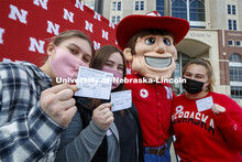 Huskers show off their vaccine cards with Herbie Husker at the after-vaccine party in the parking lo