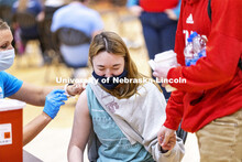 Emily Kuhl holds hands with Jacob Eckert for moral support as she receives her first dose of vaccine