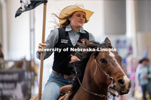 Members of the University of Nebraska rodeo team runs onto the track at the Nebraska Cornhusker Coll