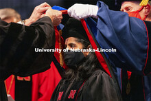 Manny Saluja is hooded by Professor Scott Sattler and Tim Carr, Associate Vice Chancellor and Dean f