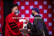 Adam Podraza receives a fist bump from Dean Richard Moberly after receiving his hood. College of Law