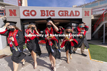 Graduates walk onto the field as they hang on to their mortar board and stoles in the brisk wind. UN