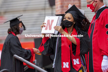 Grad gestures to her family and friends in the stadium after receiving her diploma. The university c
