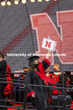 Grad holds up dipoloma as she walks off stage. The university conferred a record 3,594 degrees durin