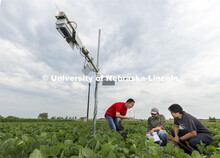 Yufeng Ge talks with Nipuna Chamara and Jun Xiao Zhang as they look over a plant remote sensor syste