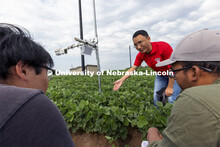 Yufeng Ge talks with Nipuna Chamara and Jun Xiao Zhang as they look over a plant remote sensor syste