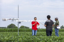 Yufeng Ge talks with Nipuna Chamara and Jun Xiao Zhang as they look over a plant remote sensor syste