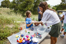 Joselyn Andreasen, a sophomore at Nebraska, helps a camper tie a string on her clay pouch. Cedar Poi