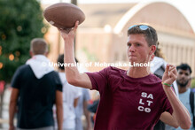 A student throws a football in hopes of winning a free bag during the Big Red Welcome Street Festiva