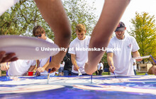Riley Berner, a senior from Norfolk, is framed by fellow painters working on “Lift Off”. Lift Of