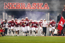 The Nebraska Football team run through a cloud of fog as they enter the field through the tunnel wal