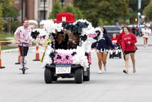 A golf cart decorated like a cow is part of the Homecoming Parade. Homecoming Parade and Cornstalk F
