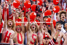 Fans with HUSKERS painted on their chests hold up their cell phone flashlights to light up the stand