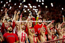 Fans with HUSKERS painted on their chests hold up their cell phone flashlights to light up the stand