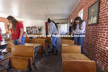 Students look at old desks saved from the school. The desks have the names of students scratched int