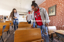 Nasia Olson-Whitefeather runs her finger along a student’s name scratched into the old desks saved