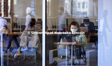 Students walking by are reflected as others study in Love Library. First day of classes for the spri