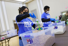 Cynthia Serrano-Ortega adds a scoop of beans to a meal being packed. Volunteers are packing more tha