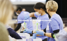 Tristen Williams adds a scoop of beans to a meal being packed. Volunteers are packing more than 2,00