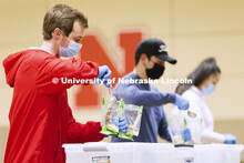 Caden Caverzagie adds a scoop of beans to a meal being packed in the Nebraska East Union. Nebraska E
