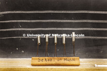 A Chalkboard Staff Liner with "School of Music" written on it is propped up on the chalkboard. The S