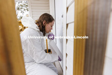 Michaela Andrusko applies a sticky sheet to the door of the house to capture a dirty handprint for e