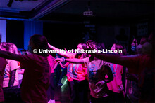 Students dancing in a "Rave"-like setting with glow lights and beach balls bouncing through the crow
