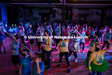 Students dancing in a "Rave"-like setting with glow lights and beach balls bouncing through the crow