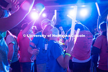 Students dancing in a "Rave"-like setting with glow lights and beach balls bouncing through the crow