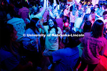 Students dancing in a "Rave"-like setting with glow lights and beach balls bouncing through the crow